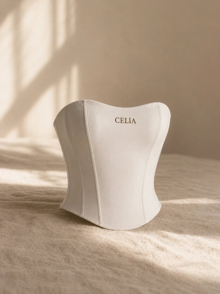 Premium e-commerce editorial packshot, studio photography style. Rest the white CELIA corset on a te
