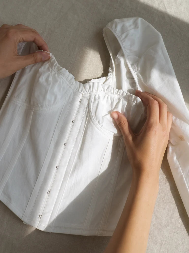 Lifestyle editorial photograph, natural light. A pair of feminine hands, manicured but natural, adju