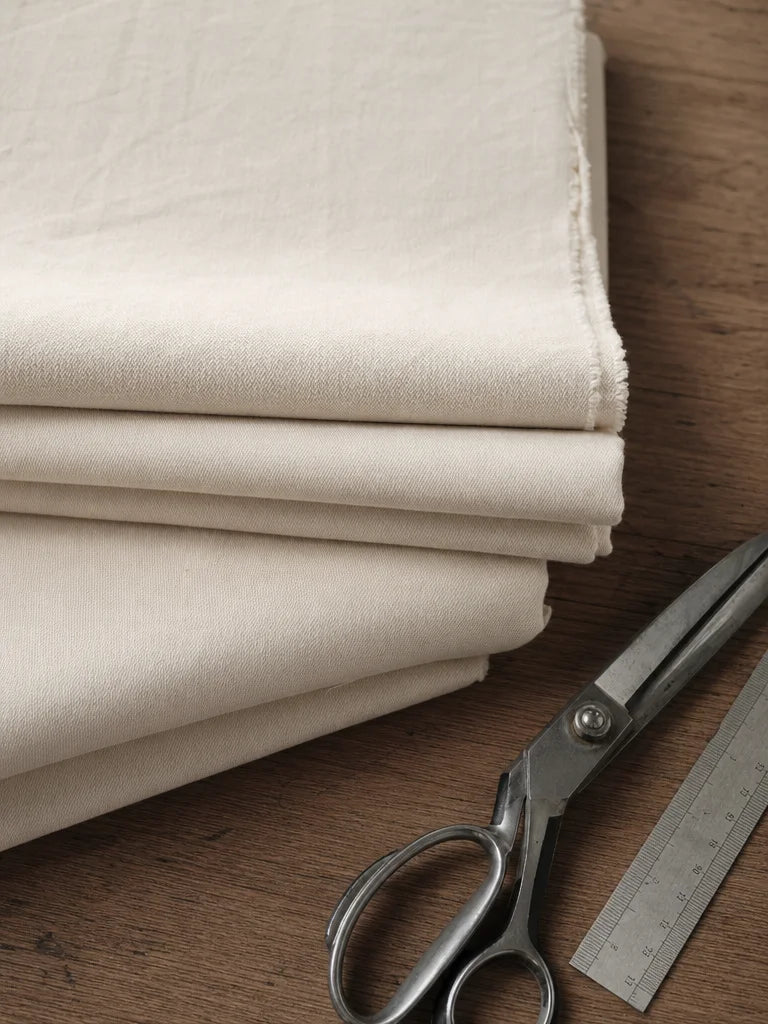 Editorial magazine still-life photograph, overhead styling. A carefully folded stack of premium fabr